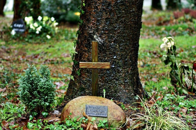 Grabstelle mit Holzkreuz an einem Baum